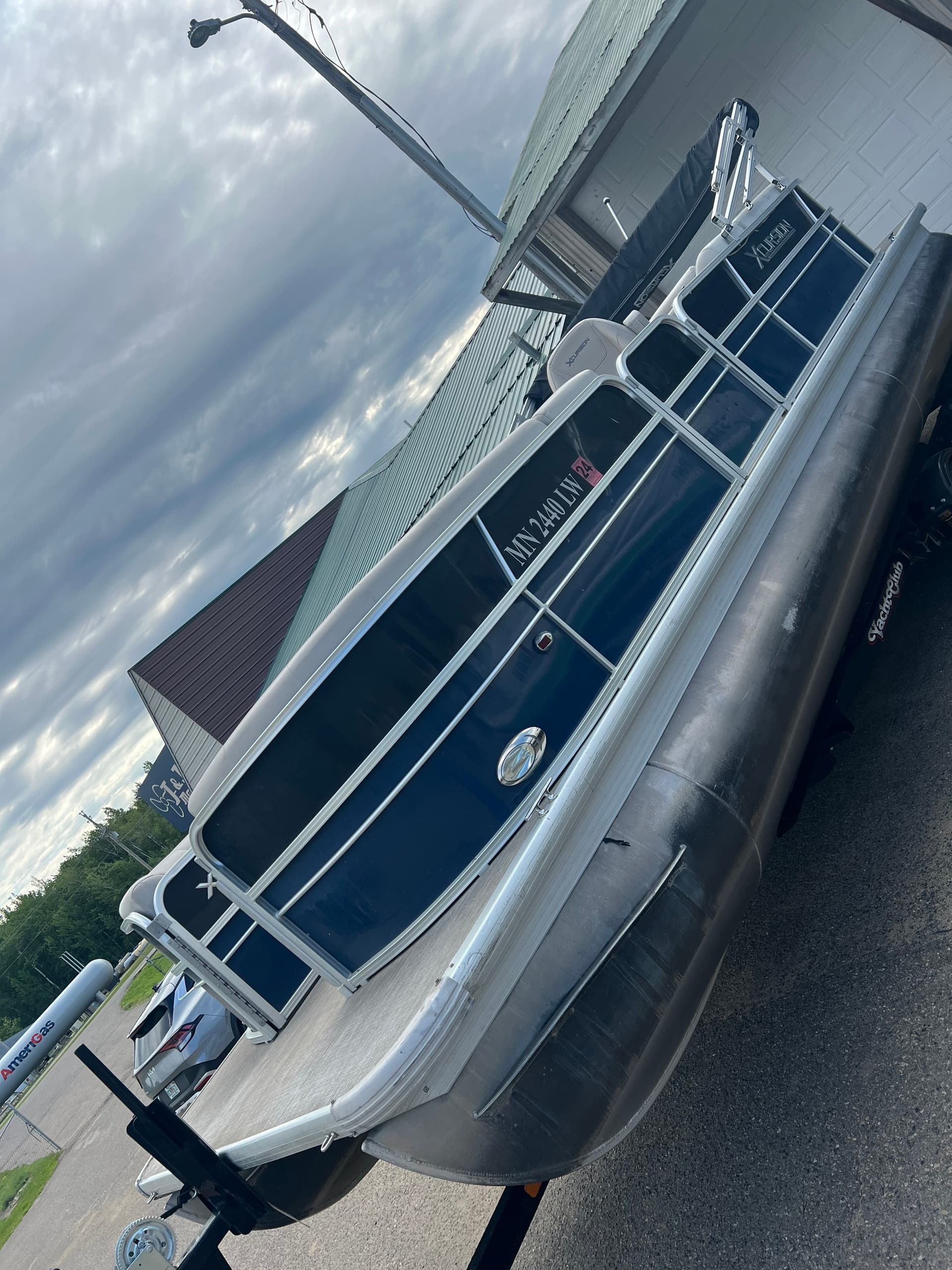 Pontoon boat parked outdoors on trailer beside marina