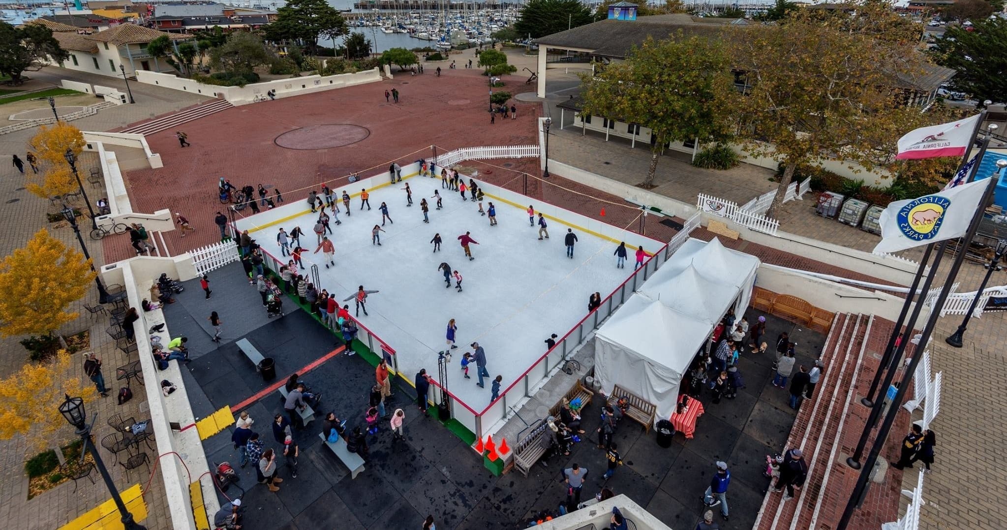 Outdoor ice skating rink at seaside plaza with skaters