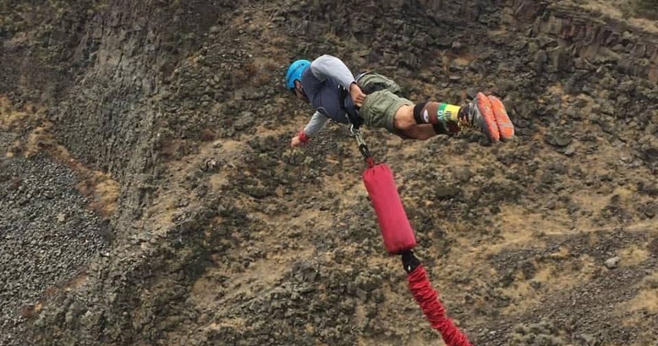 Jumping off bridge bungee with red rope against rocky cliffs