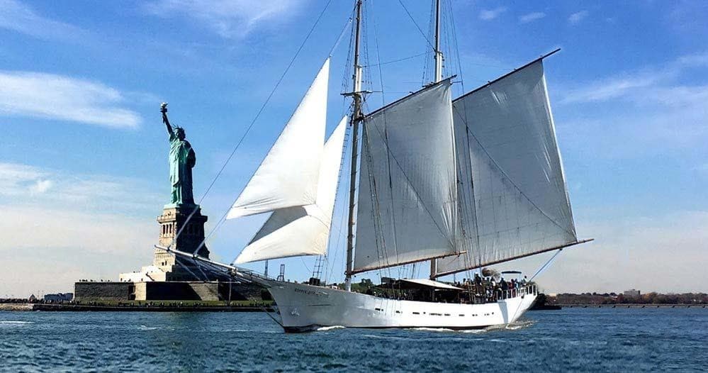 White schooner sailing past Statue of Liberty in NYC harbor tour