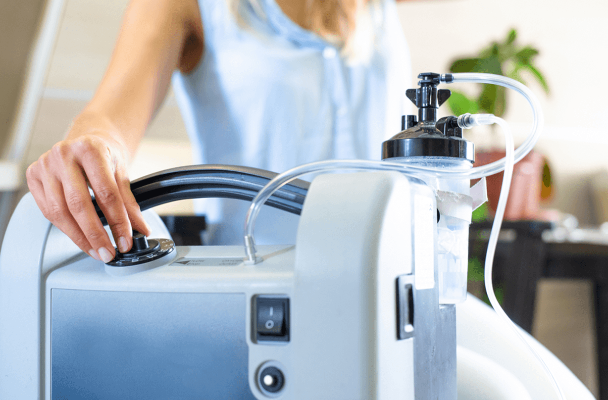 Hand adjusting portable oxygen concentrator machine in home setting