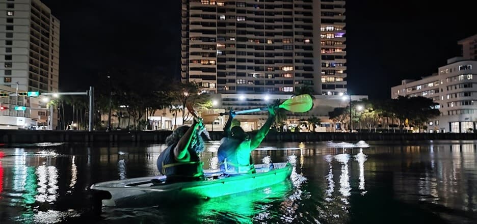 Night kayaking illuminated green tour in urban Miami waterway