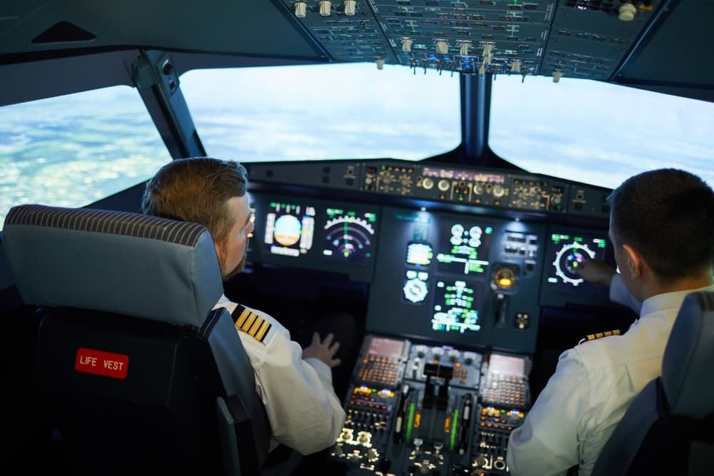 Commercial pilots navigating aircraft cockpit during flight