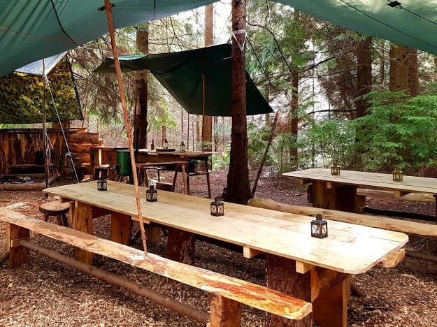 Rustic outdoor dining shelter with picnic tables at forest basecamp