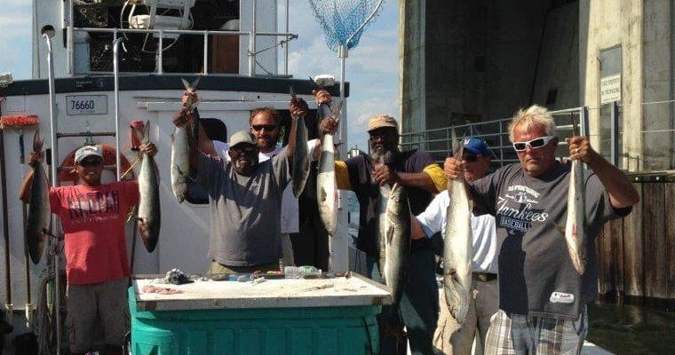 Group of fishermen holding fresh catch on docked sportboat