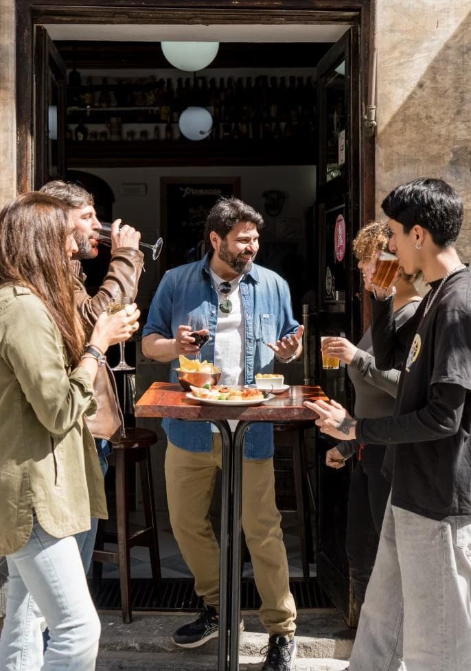 Group savoring drinks and pintxos outside a Madrid bar doorway
