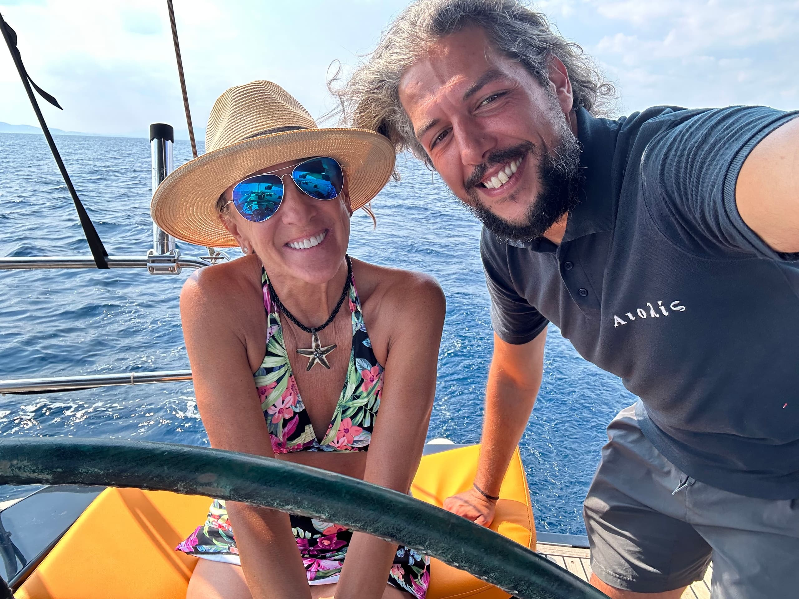 Couple smiling aboard sailboat on open sea, sailing experience