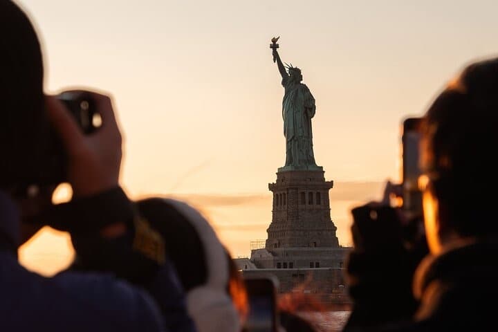Viewers photographing Statue of Liberty at sunset cruise