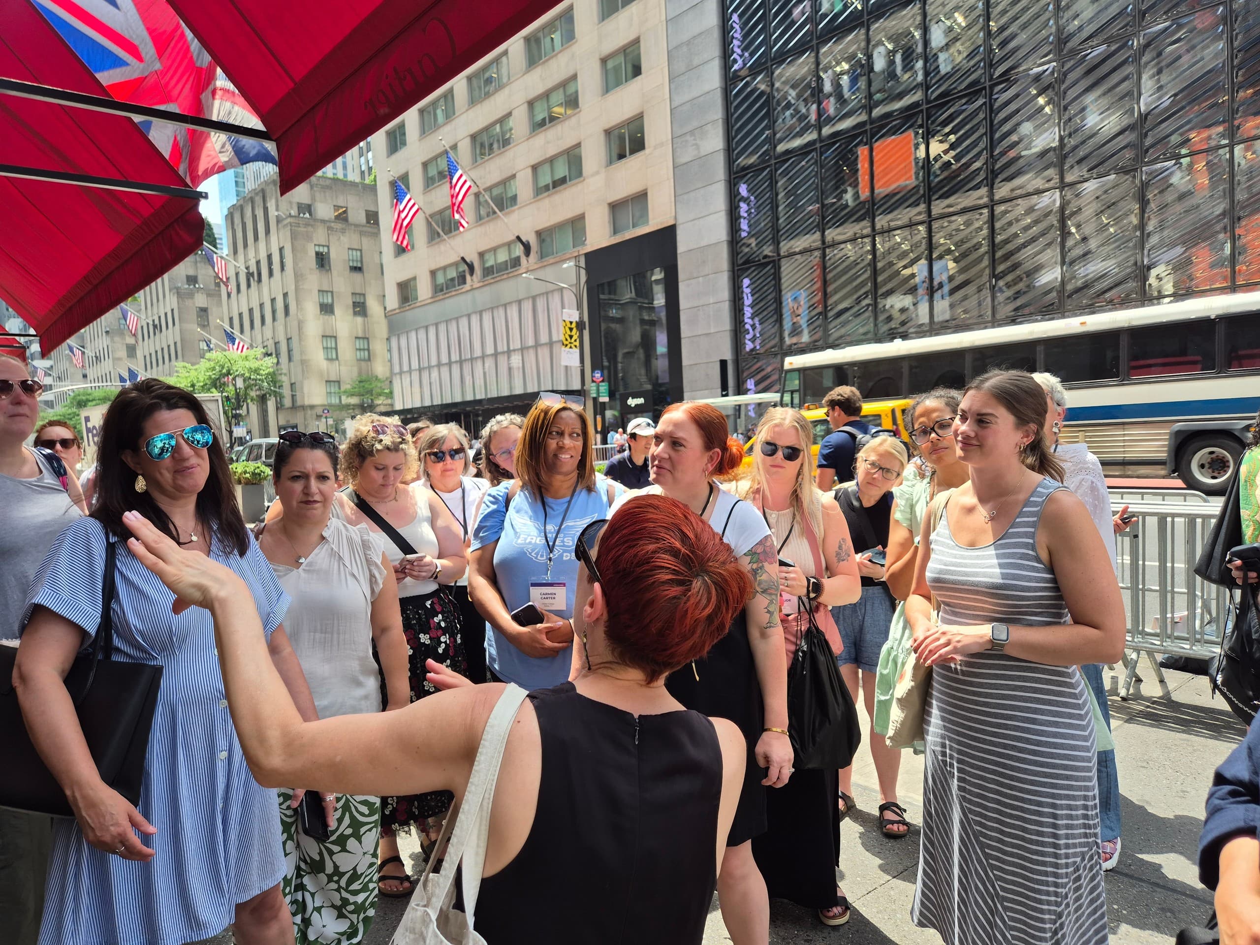Large guided tour group gathered under red awnings on NYC sidewalk