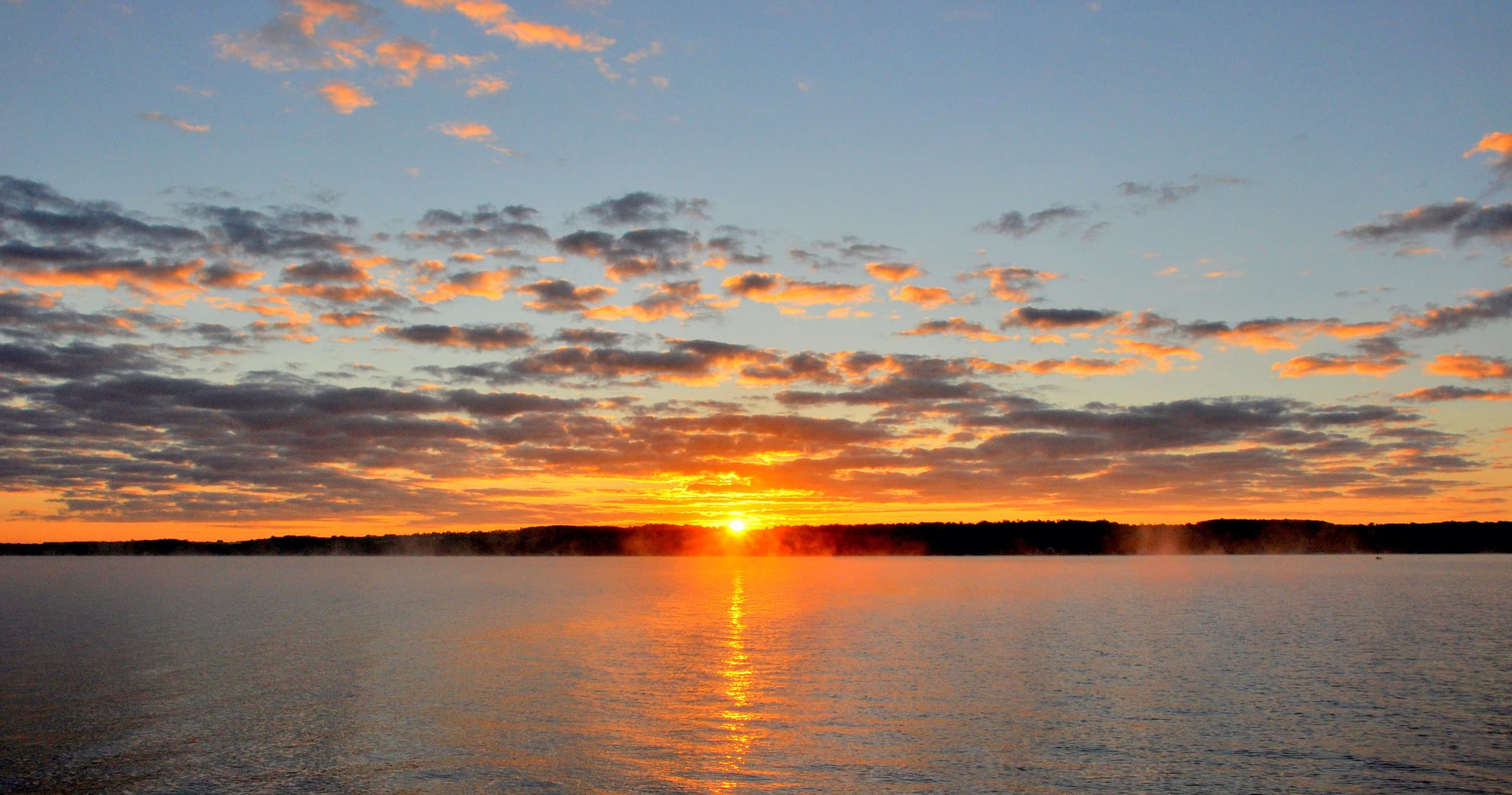 Vibrant sunset over calm lake, evening paddling silhouette
