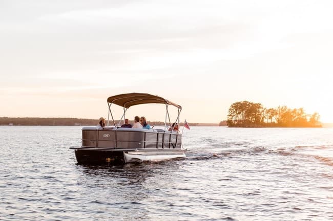 Pontoon boat cruising at sunset on calm recreational lake