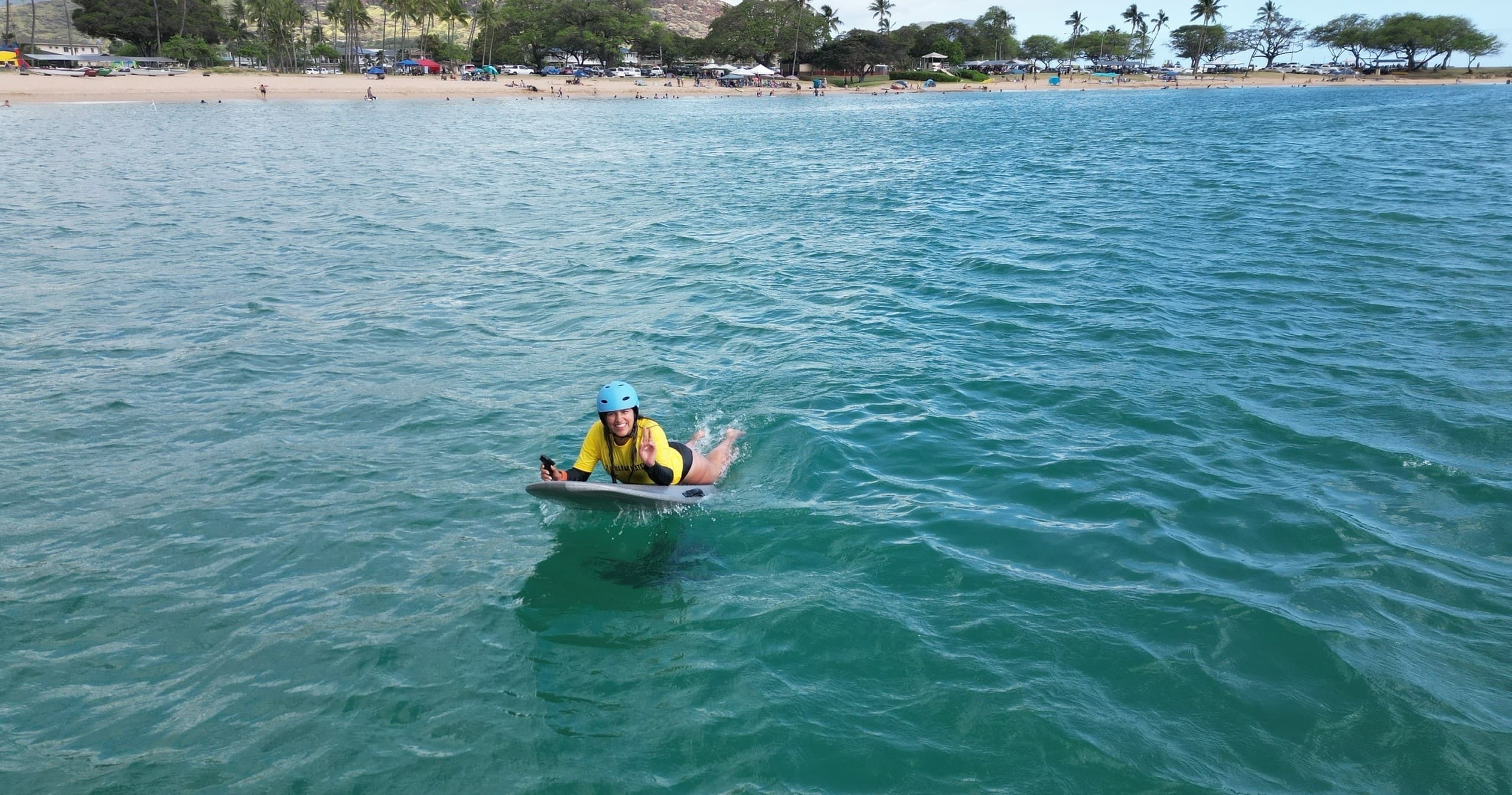 Bodyboarder riding turquoise ocean near sandy tropical beach