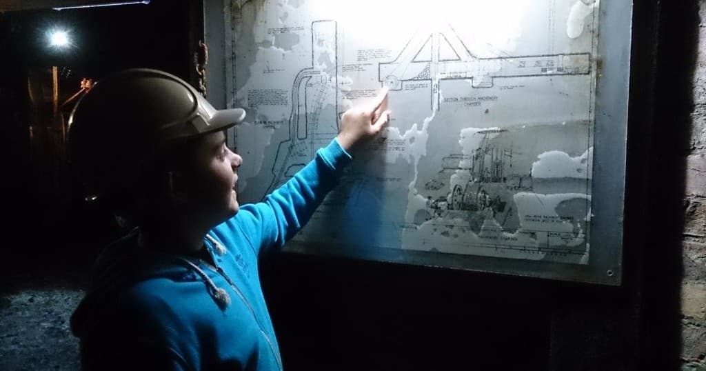 Visitor studying mine diagram during underground tour visit