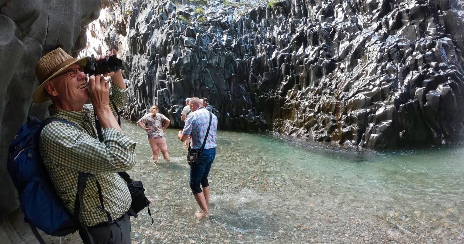 Photographer and guides wading through scenic basalt gorge river
