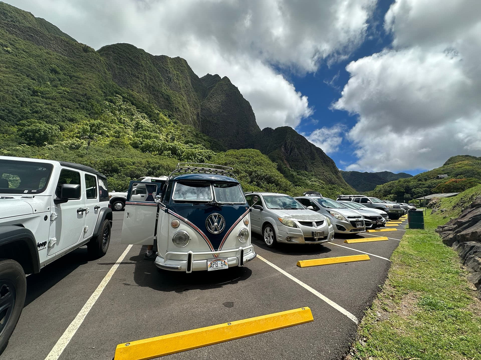 Vintage VW van parked at mountain trailhead under cloudy sky