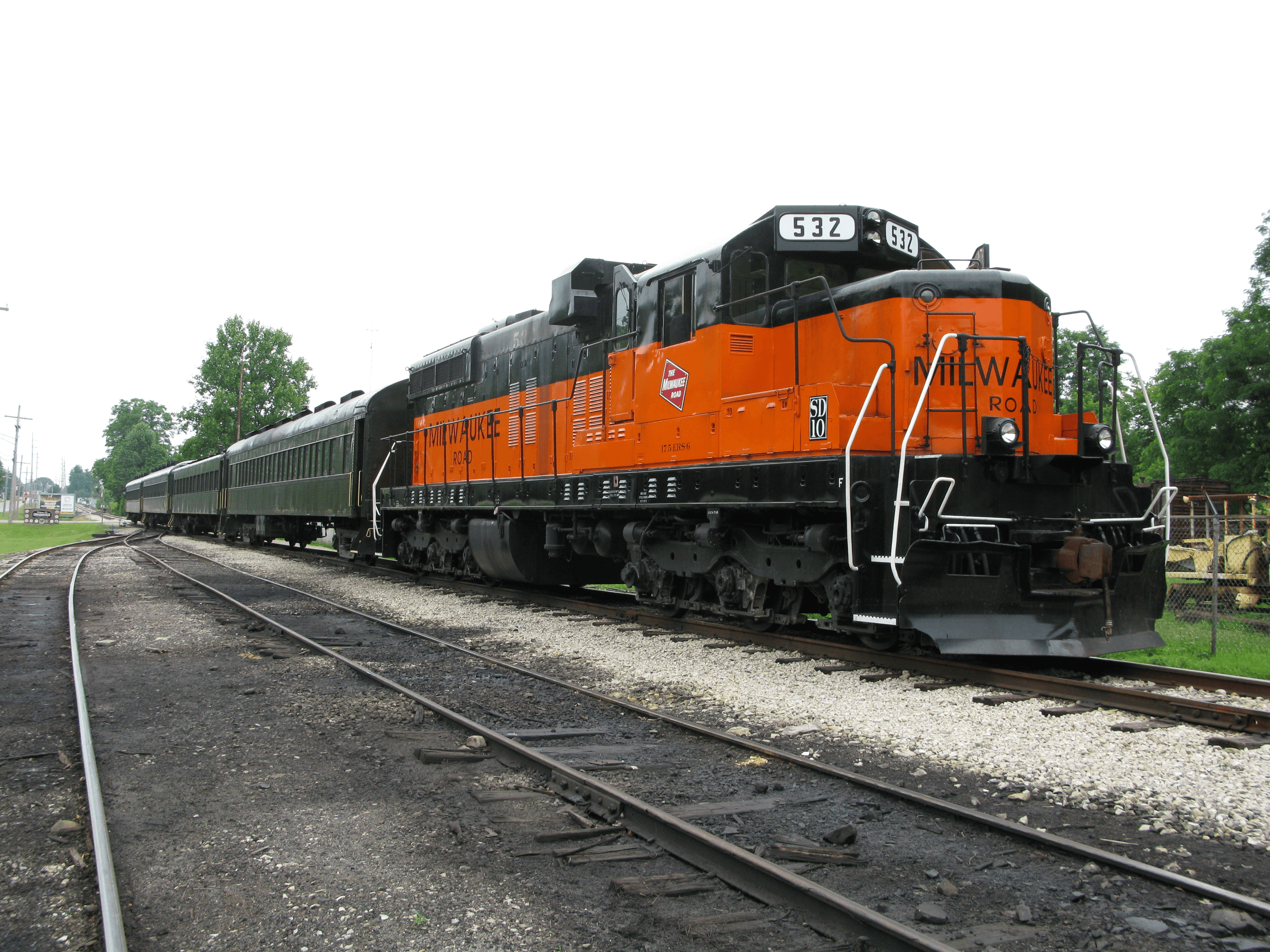 Orange heritage train parked at station platform, outdoor rail excursion