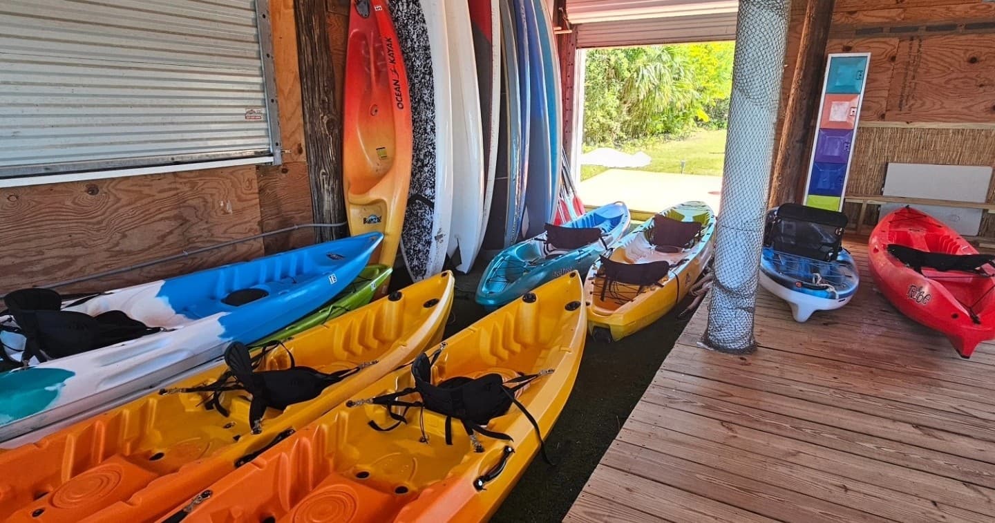 Colorful rental kayaks lined inside wooden boathouse, ready to launch