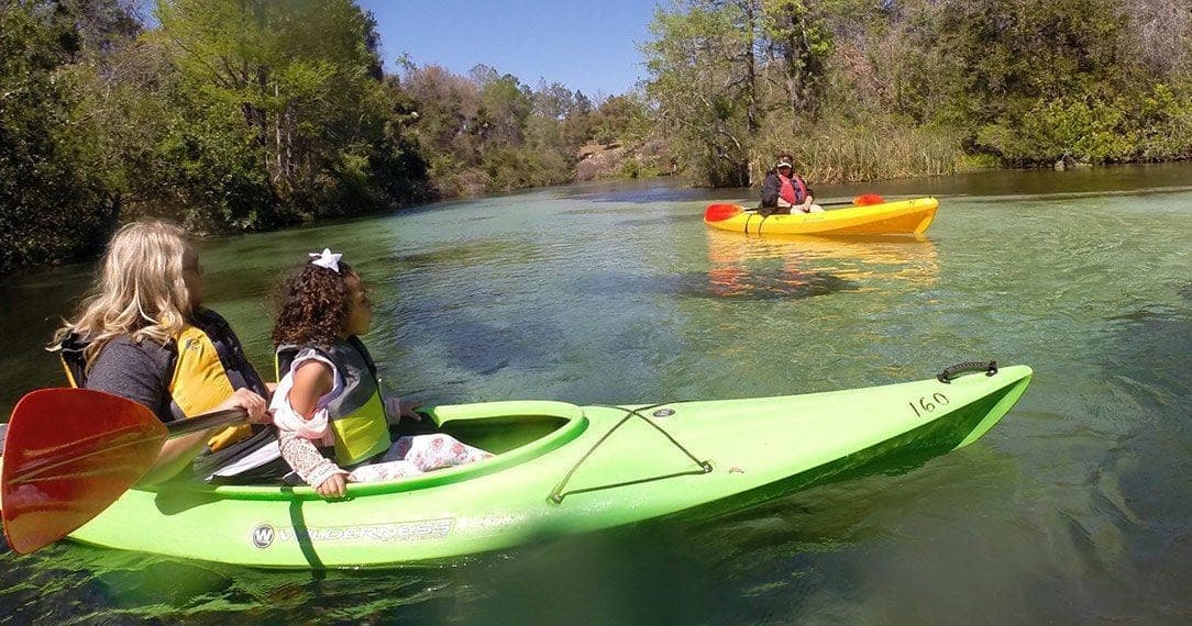 Family kayaking on calm clear spring river, paddling together