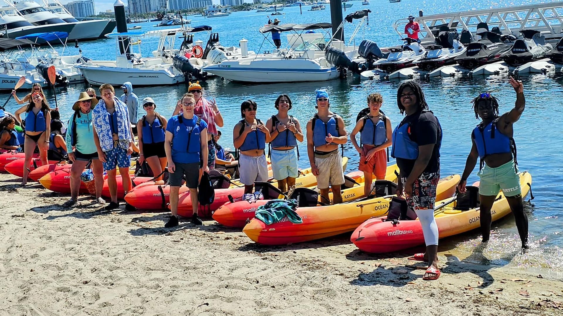 Group kayaking along sunny shoreline with calm blue ocean waters