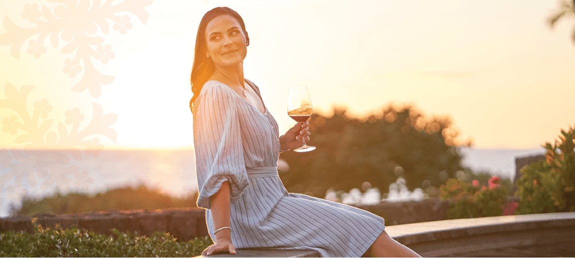 Woman enjoying wine at Mauna Kea resort terrace at sunset