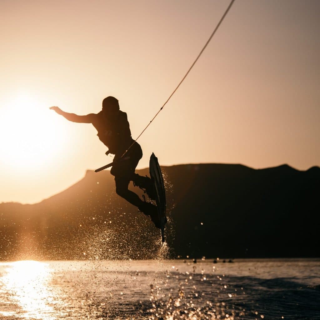 Sunset wakeboarder jumping silhouetted against warm glowing sky
