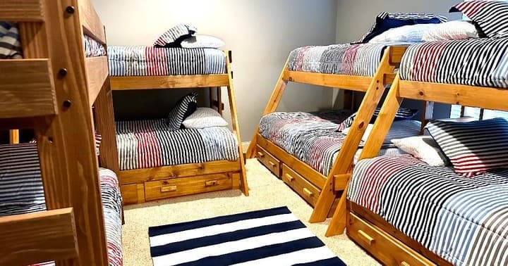 Shared bunkroom with multiple wooden bunks and striped linens