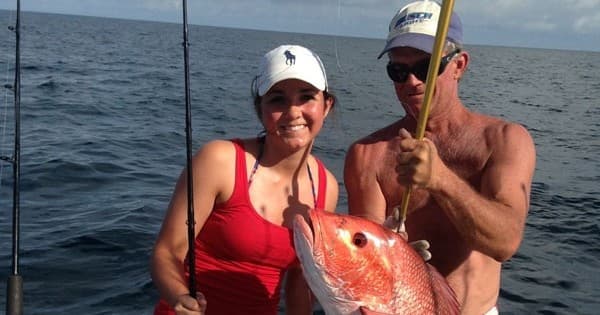 Couple holding red snapper on deep sea fishing charter
