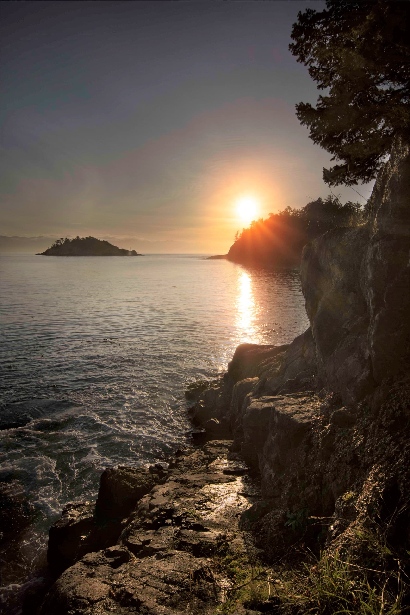 Sunset over rocky coastal cliffs with golden light, ocean viewpoint