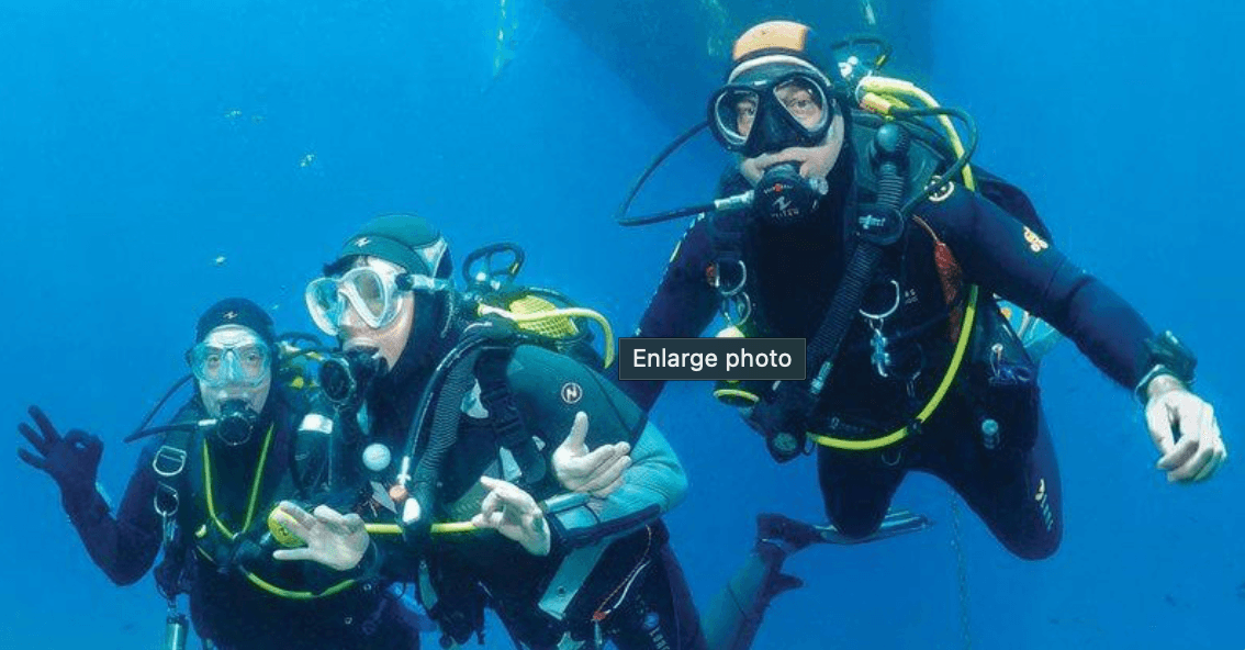 Group of scuba divers posing midwater on tropical reef dive