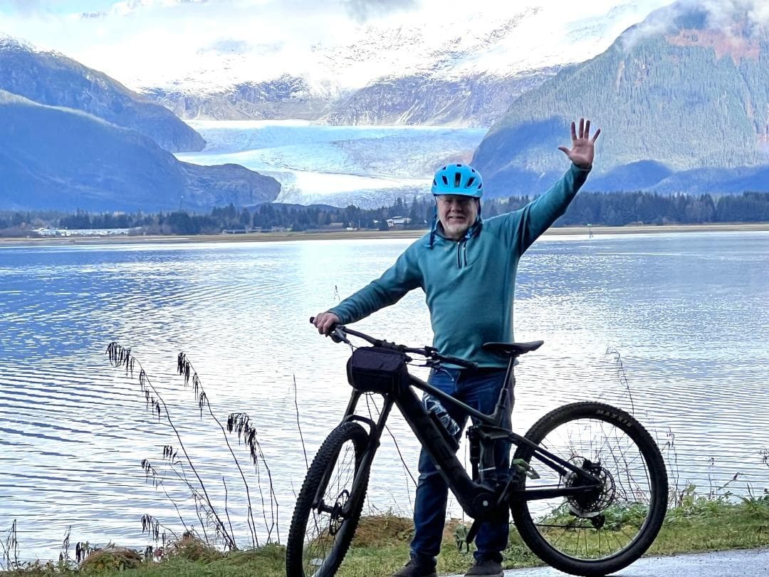 Cyclist posing with mountain lake and glacier views in Alaska