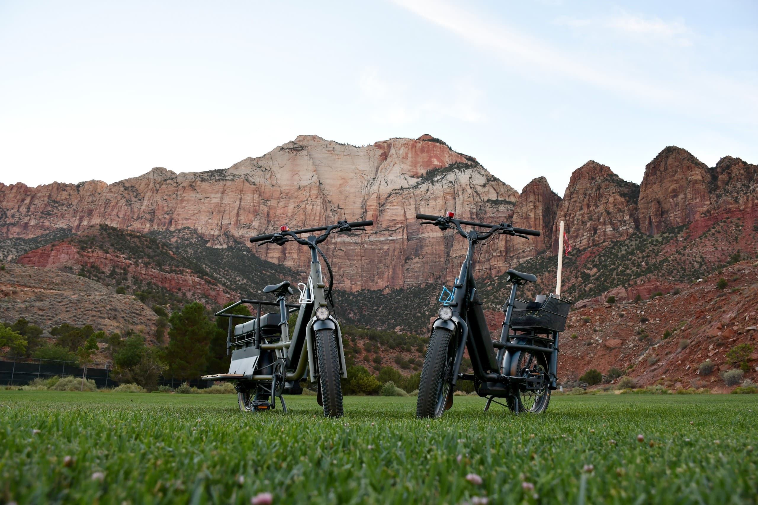 Electric bikes parked on grass with Zion cliffs at sunset