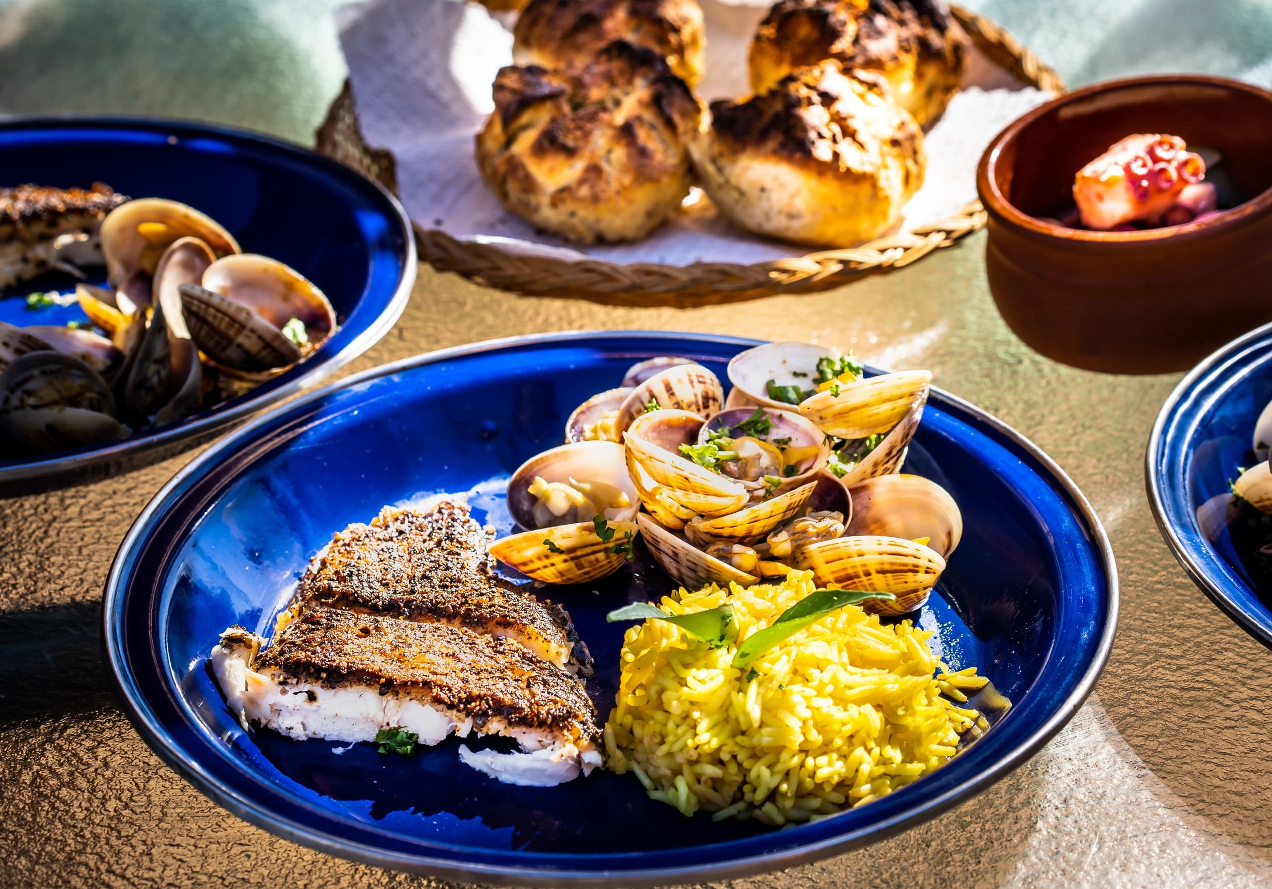 Seafood platter with clams and rice served on blue plates at table