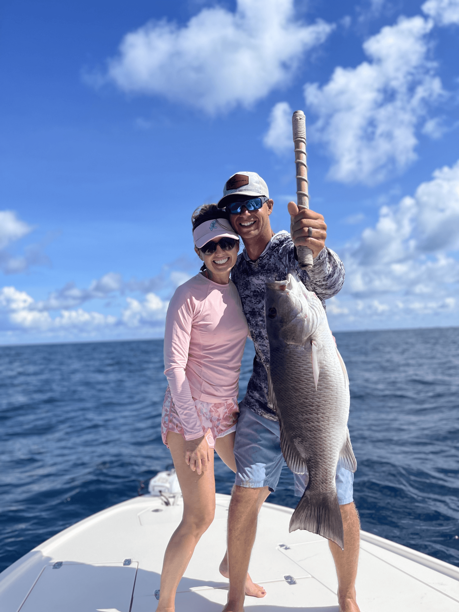 Couple posing with large deep-sea fish aboard offshore charter