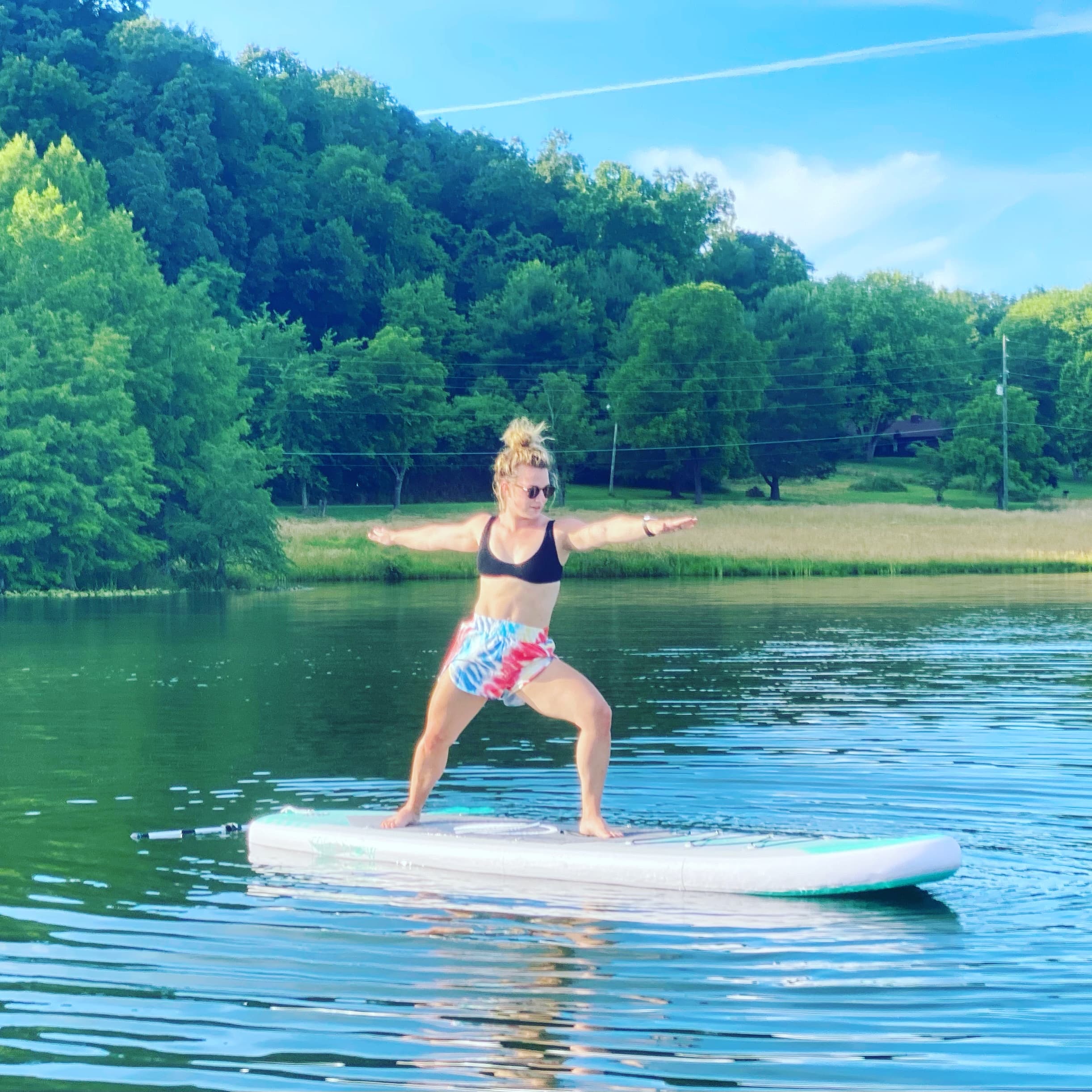 Stand-up paddleboard yoga on a scenic lake with forested hills