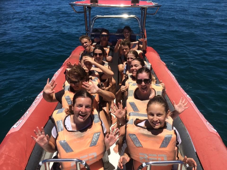 Smiling passengers on red RIB boat enjoying ocean tour