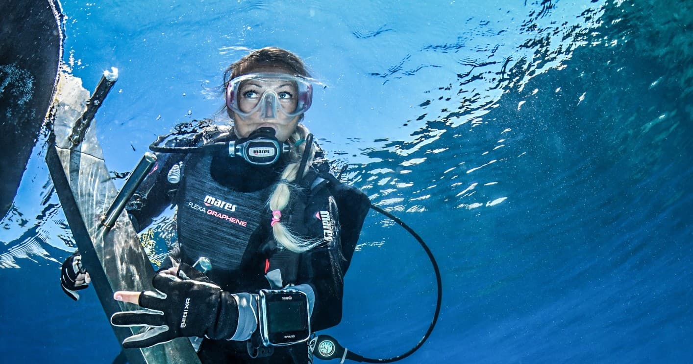 Scuba diver ascending near boat in clear blue coastal waters