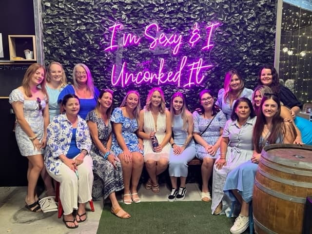 Group wine tasting event under neon sign at Sutton Estate venue