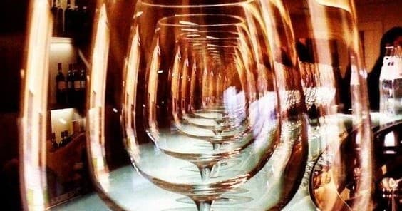 Artistic repeated wine glasses in dim indoor tasting room reflection