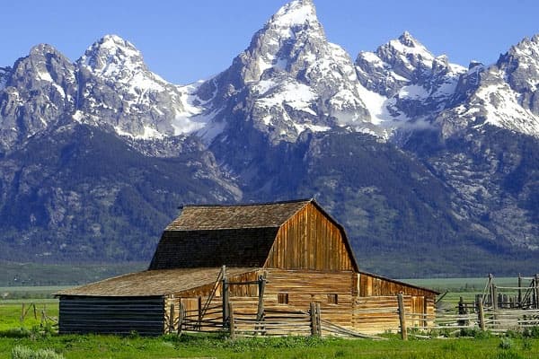 Historic barn beneath Teton mountains at sunrise in alpine valley