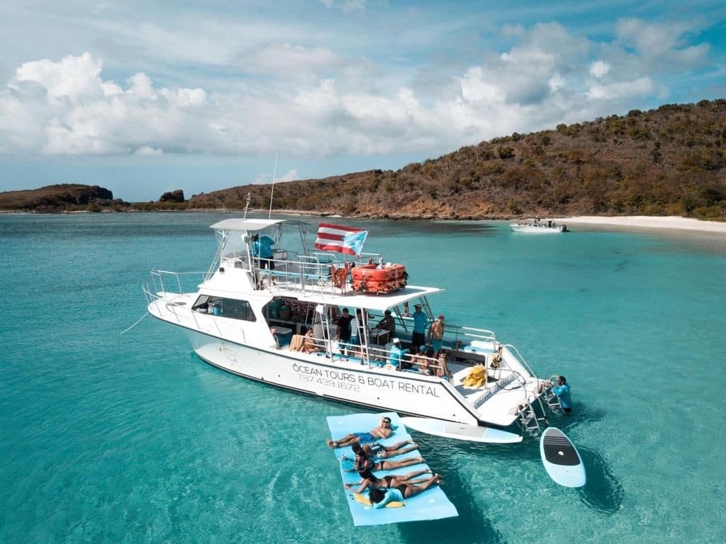 Day charter boat moored in shallow turquoise cove with guests