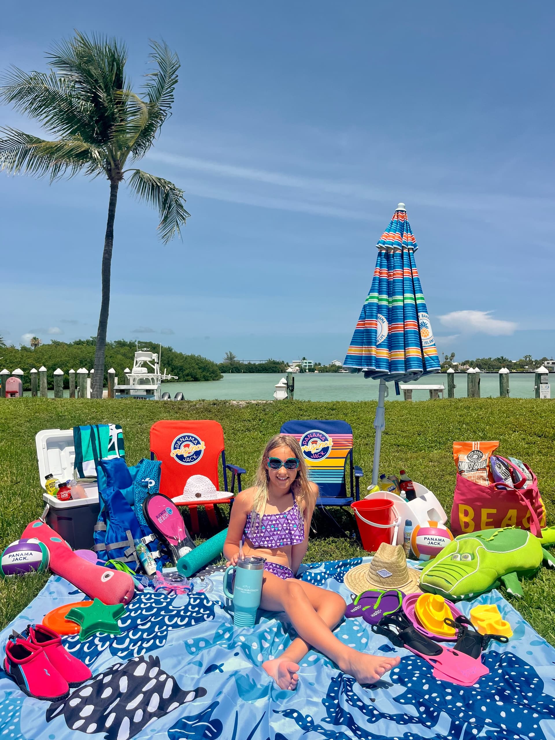 Woman relaxing with beach gear at waterfront park under umbrella