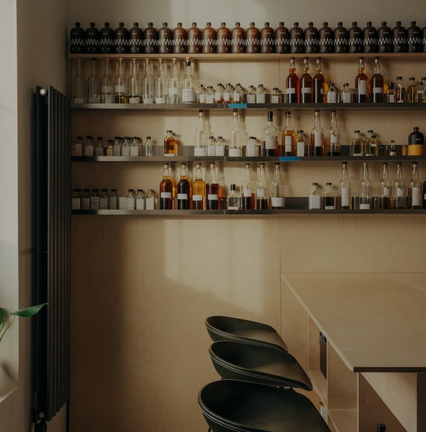 Interior whisky bar with bottle-lined shelves and stools