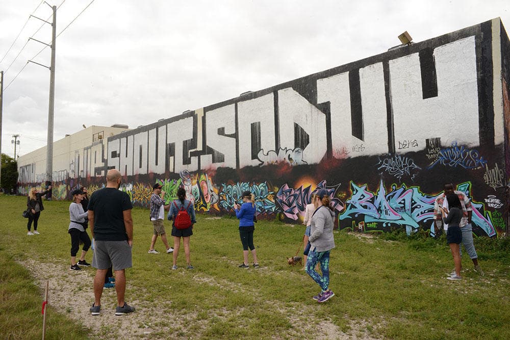 Visitors exploring large Wynwood mural wall in Miami outdoors
