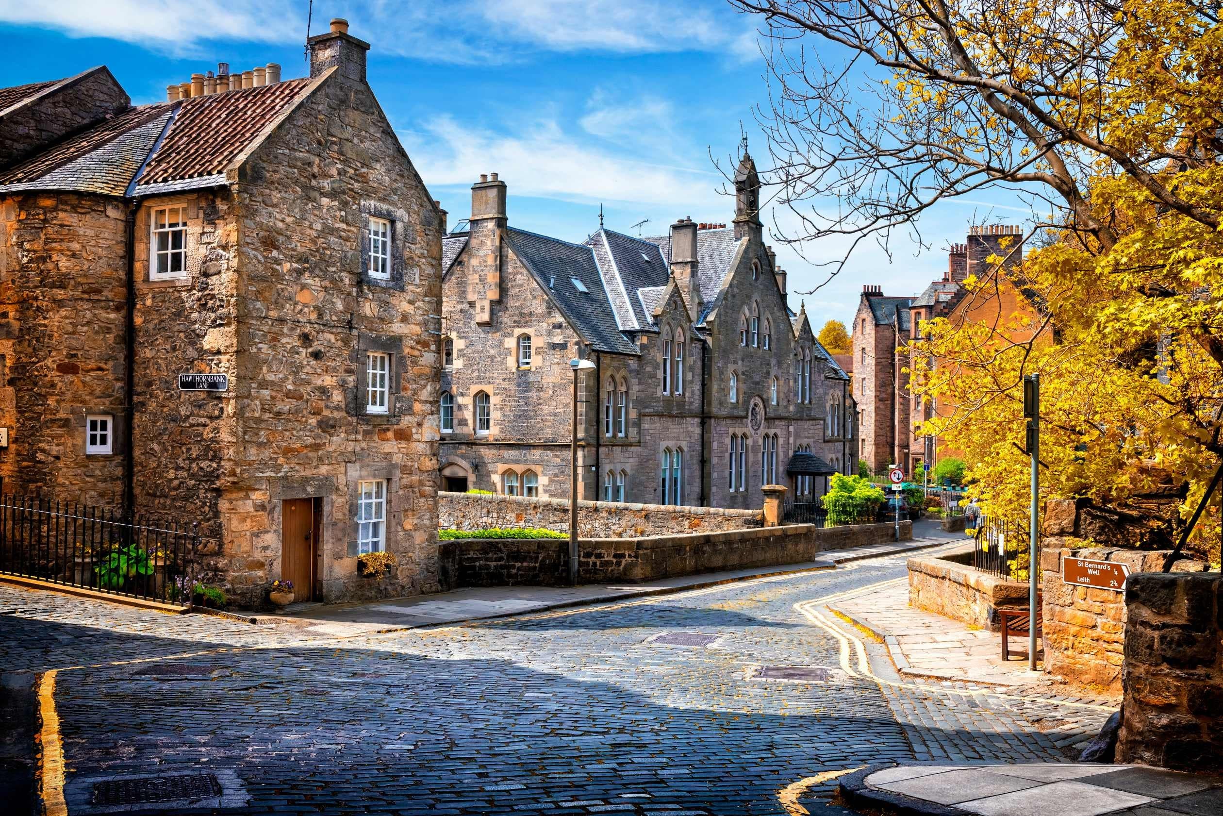 Historic village stone street with cobblestones and autumn trees