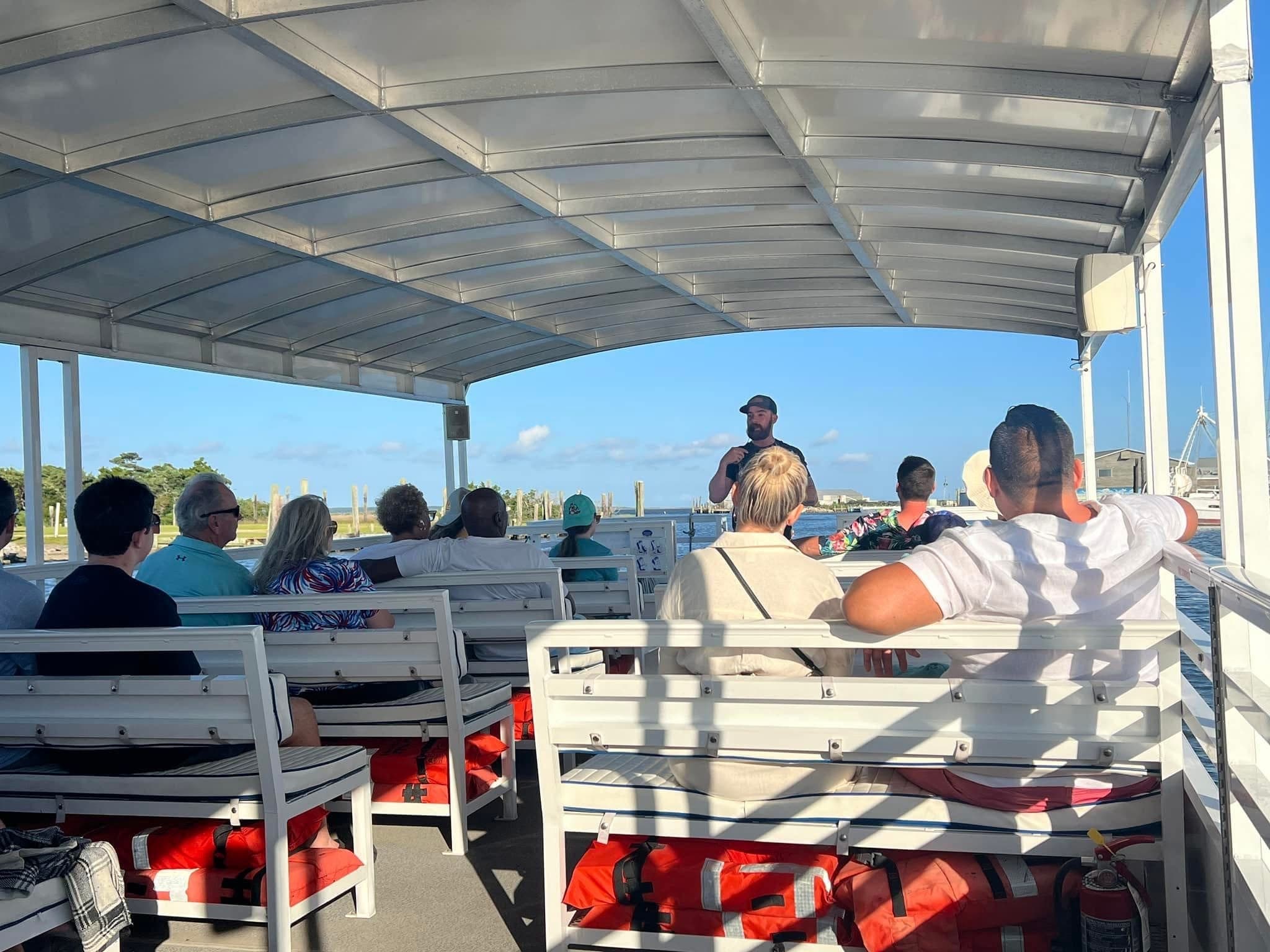 Passengers on covered sightseeing boat departing marina at sunset