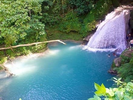 Blue natural pool and waterfall in lush Jamaican rainforest