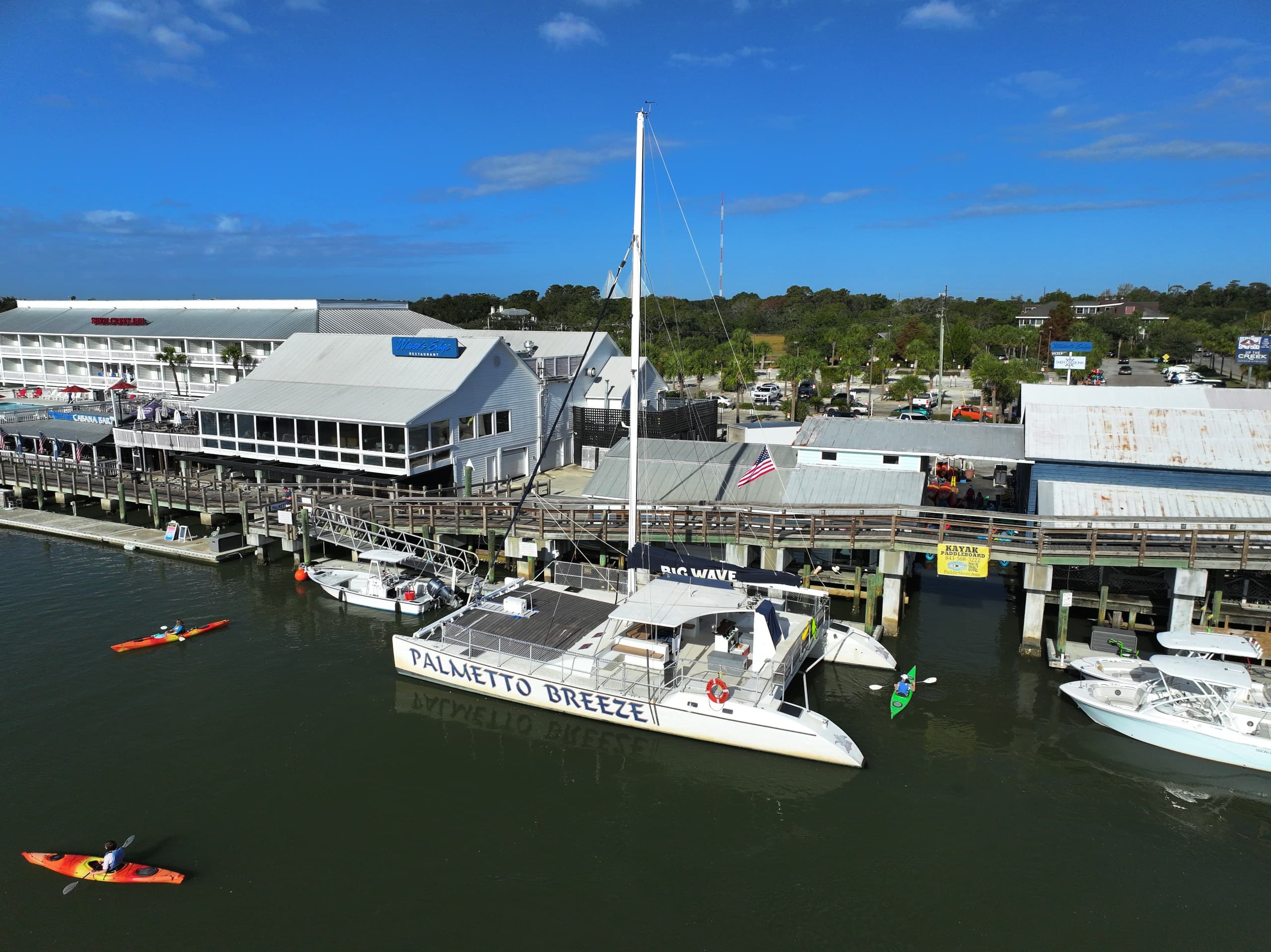 Docked catamaran and kayaks beside waterfront marina buildings