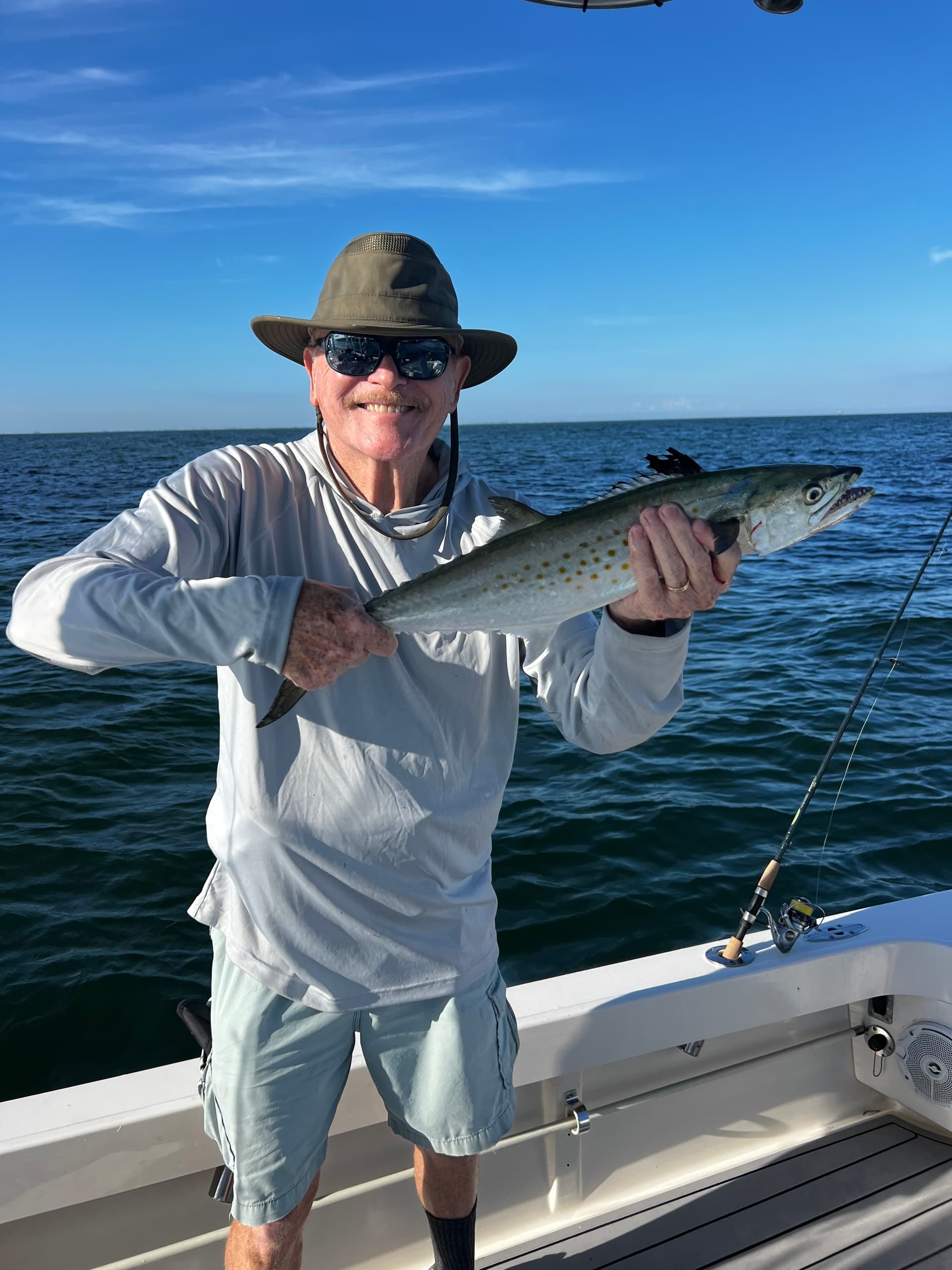 Angler posing with kingfish on a sportfishing boat in open ocean