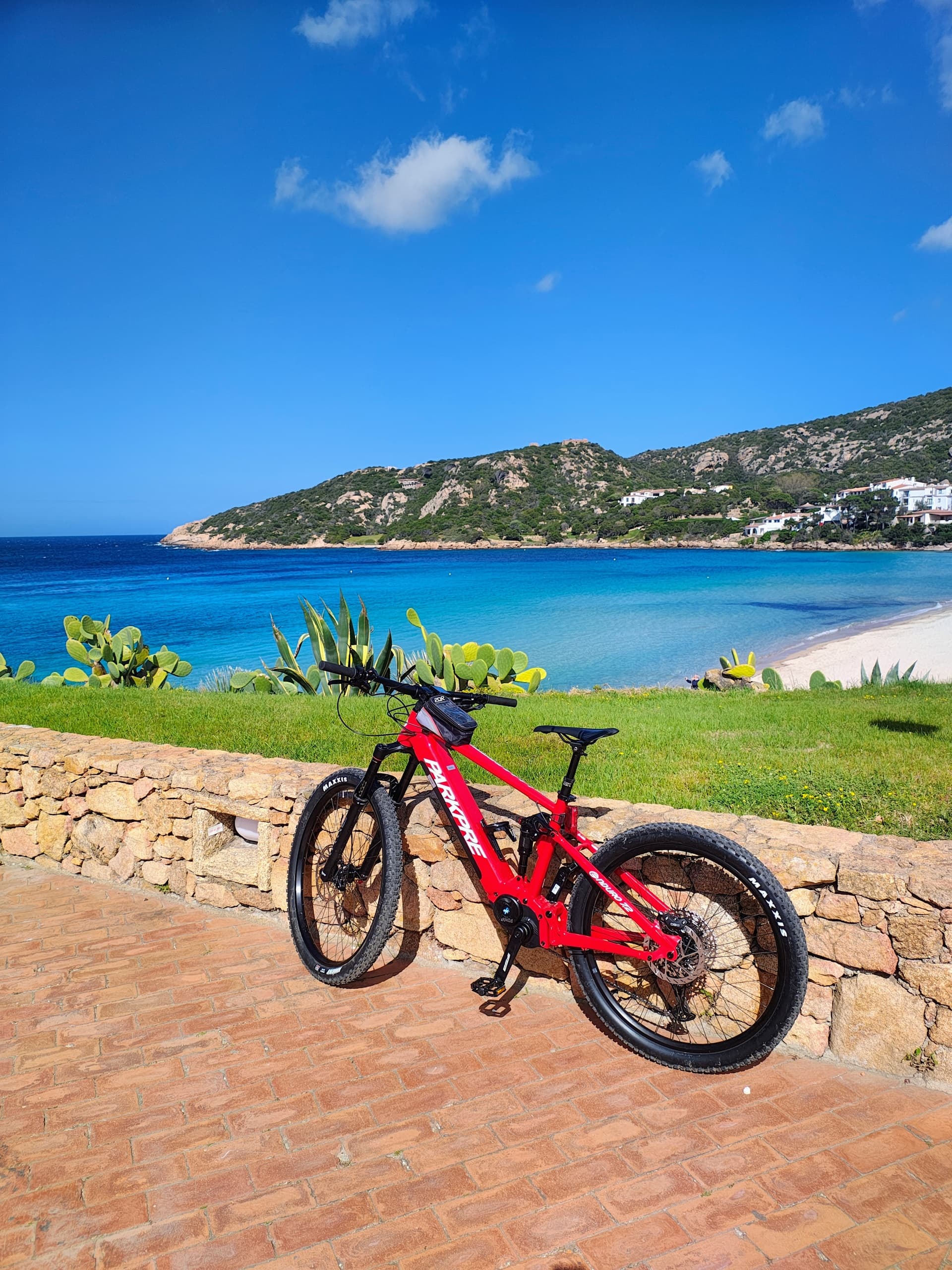 Red e-bike parked overlooking turquoise beach and coastal bluff