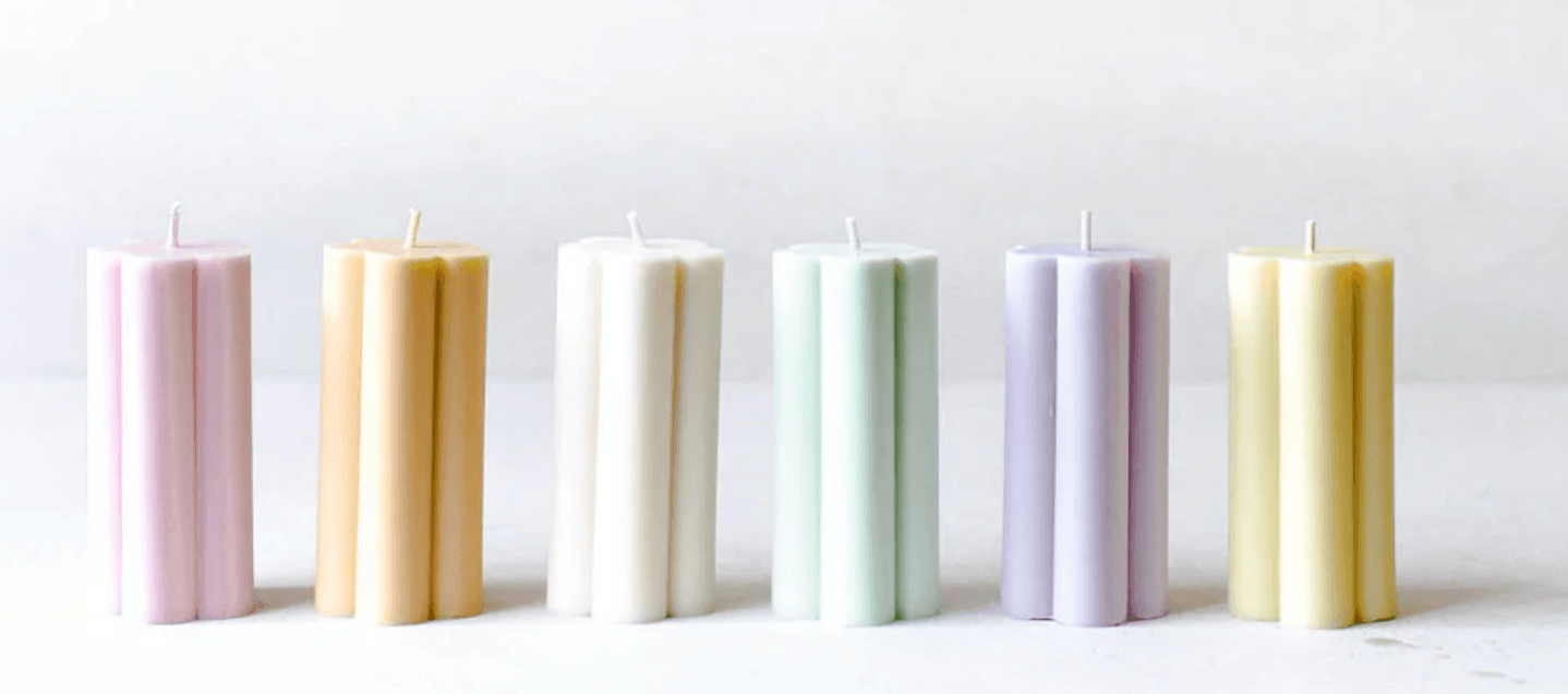 Row of pastel candles product display on white studio background